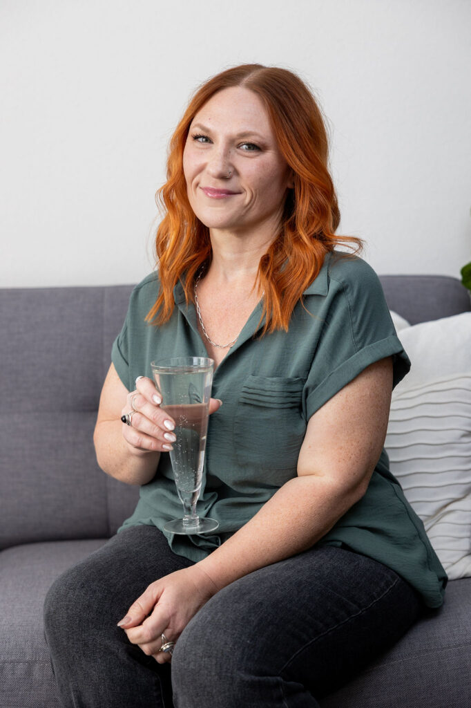 Small business bookkeeper sitting on a sofa holding a glass, representing a calm and confident close to the business year.